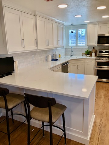 White kitchen with island and bar stools by Oakridge Cabinet and Design