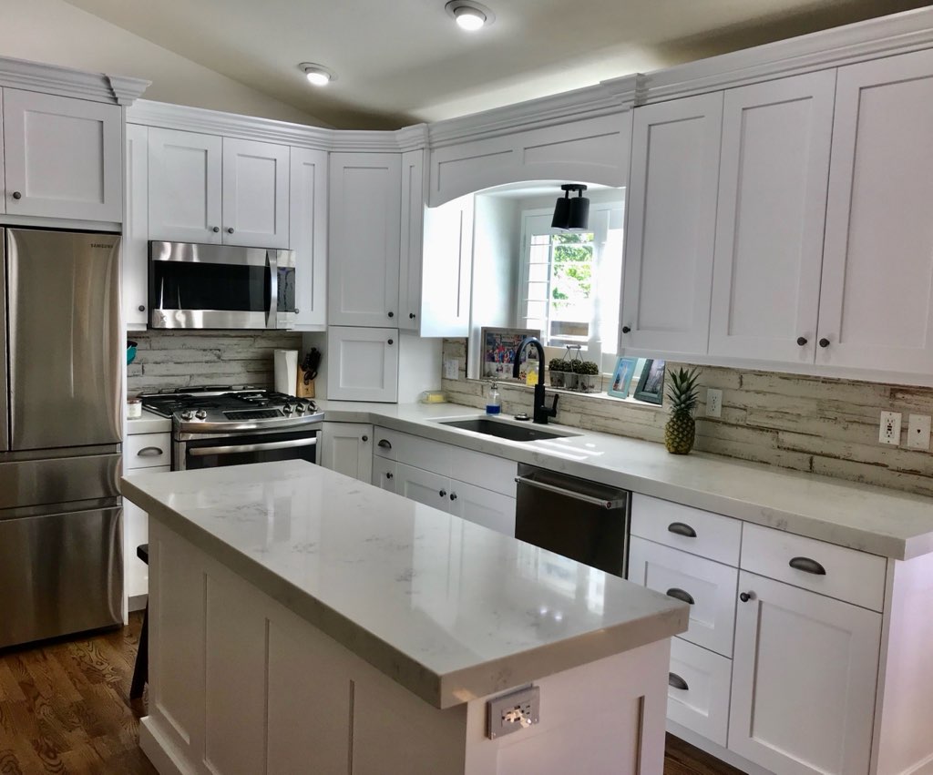 White kitchen with marble island by Oakridge Cabinet and Design